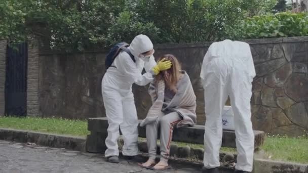 Doctors in protection suits caring woman - Záběry, video