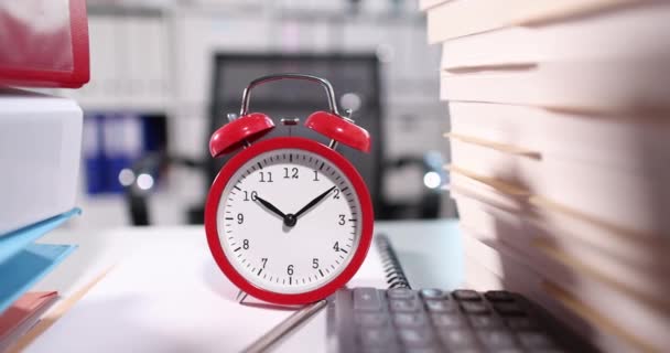 Red alarm clock for ten oclock on desktop with documents - Filmati, video