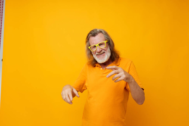 Photo of retired old man yellow t-shirt and glasses posing yellow background - Foto, imagen