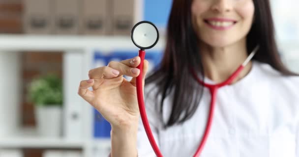 Smiling female doctor in white coat is holding stethoscope - Video