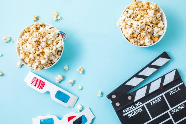 Cinema minimal concept. word movie, popcorn, clapperboard, 3D glasses and tickets top view flat lay on blue background - Фото, зображення