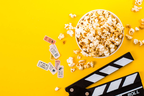 Bowl of salty popcorns on a yellow background. Cinema snack concept. Flat lay top view - Foto, Imagem