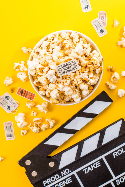 Bowl of salty popcorns on a yellow background. Cinema snack concept. Flat lay top view - Zdjęcie, obraz