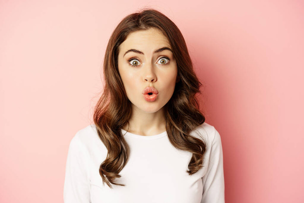 Image of stylish glamour woman looking surprised and amazed, saying wow with impressed reaction, standing over pink background - Fotografie, Obrázek