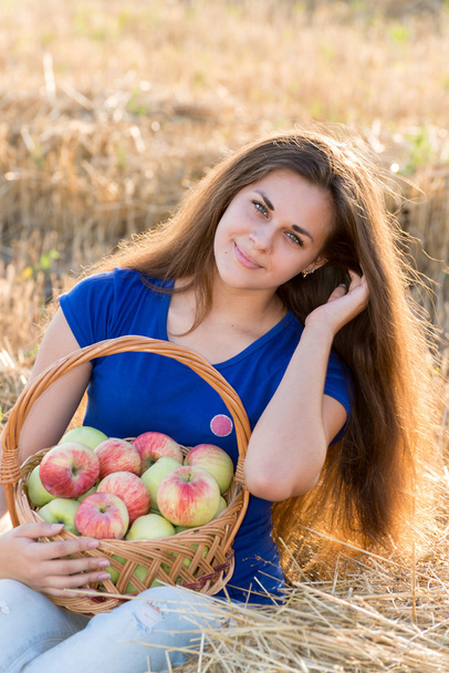 Teen girl with a basket of apples in  field - Photo, Image