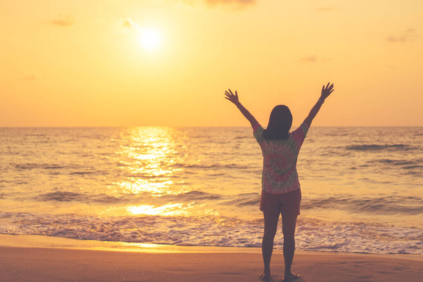 Copy space of woman rise hand up on sunset sky at beach and island background. Freedom and travel adventure concept. Vintage tone filter effect color style. - Foto, imagen