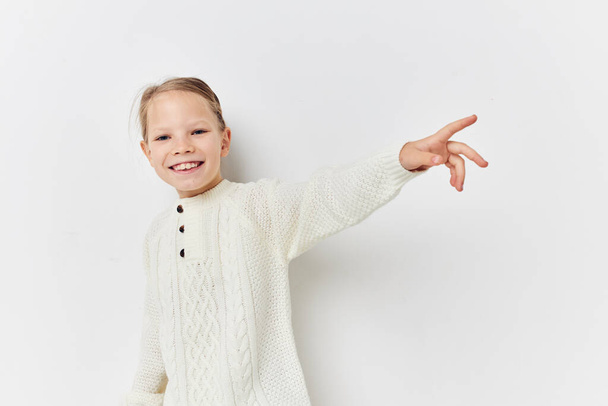 cheerful little girl in a white sweater hand gesture - Valokuva, kuva