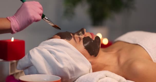 Woman rejuvenating face cream brush and a face mask applied - Footage, Video