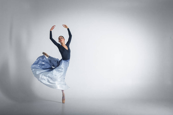 バレリーナ。プロの服装、靴、青い無重力のスカートを身に着けている若いエレガントなバレエダンサーは、彼女のダンススキルを示しています。古典バレエの美しさ - 写真・画像
