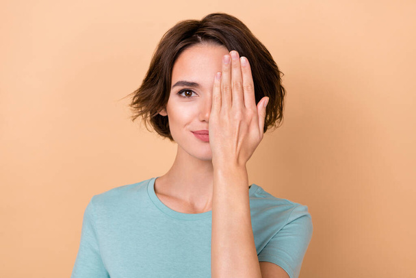 Fotografie mladé hezké ženy kryt oko ruka pohled klinika kontrola vidění izolované přes béžové barvy pozadí. - Fotografie, Obrázek