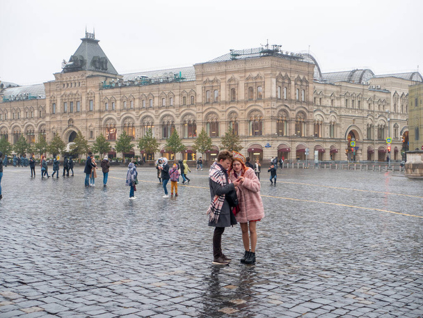 People walk and take pictures on Red Square on an autumn day. The girl in the Russian national headdress kokoshnik. Russia. Moscow. 05.10.2021. - 写真・画像