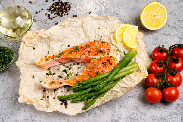 raw fresh salmon steak and asparagus with tomato branch on parchment - Photo, image