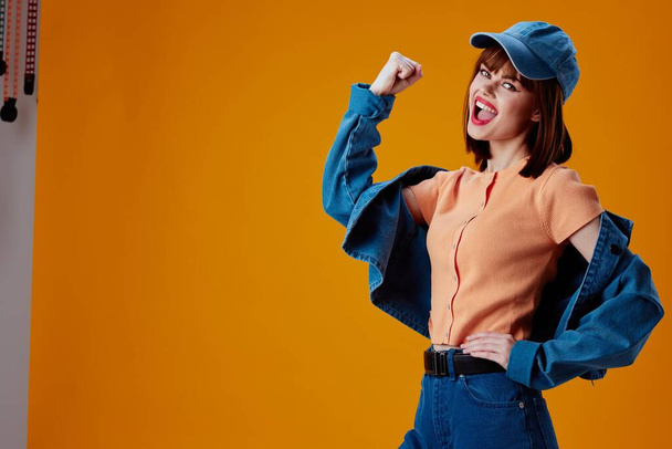 Pretty young female in a cap and denim jacket posing color background unaltered - Photo, Image