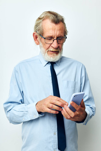 Senior grey-haired man in a shirt with a tie talking on the phone cropped view - Fotó, kép