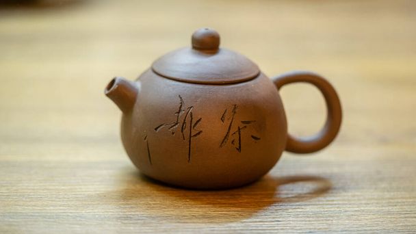Traditional clay teapot with green tea. Clay teapot on wooden background - Photo, image