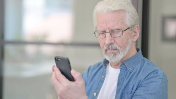 スマートフォンでインターネットを閲覧する老人 - 写真・画像