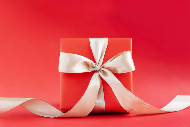 Red gift box or present box with ribbon on red background. Happy Birthday or Valentine's Day concept. - Foto, afbeelding