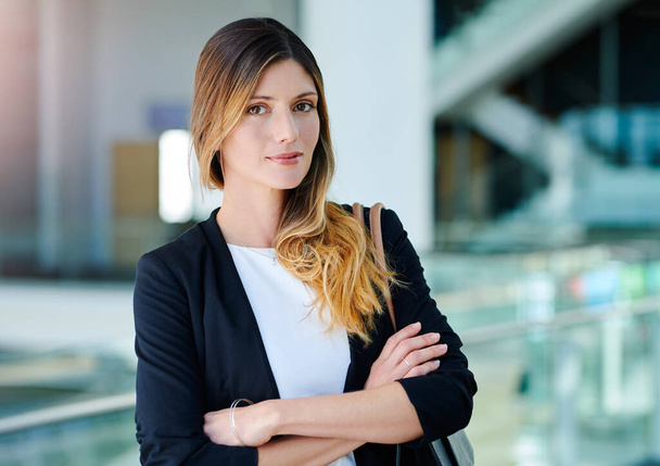 Stand tall and be bold. Cropped portrait of an attractive young businesswoman standing with her arms crossed in an office. - Фото, изображение