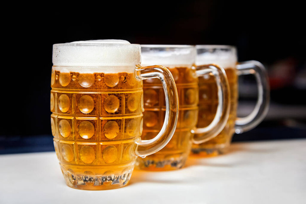 Three glasses of fresh foamy beer on the bar counter - Foto, Bild
