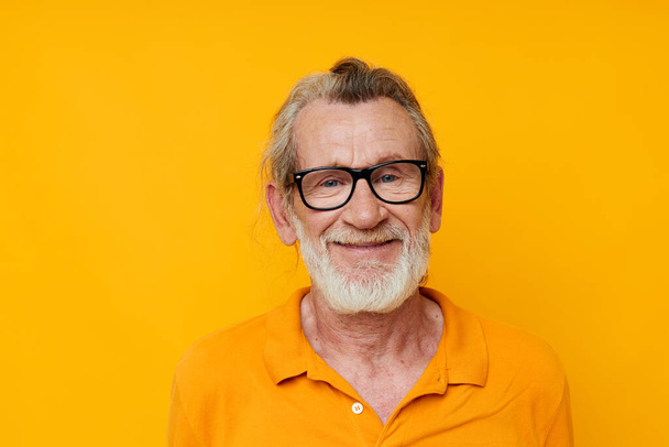an elderly man with glasses in a yellow t-shirt with glasses close-up - Foto, immagini