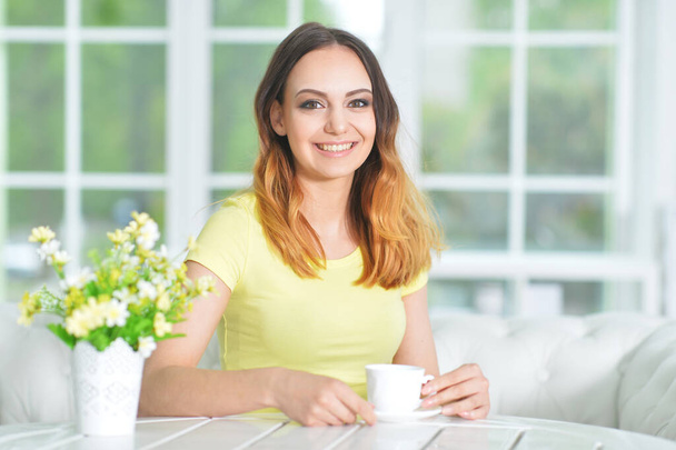 mooie jonge vrouw met kopje thee thuis - Foto, afbeelding