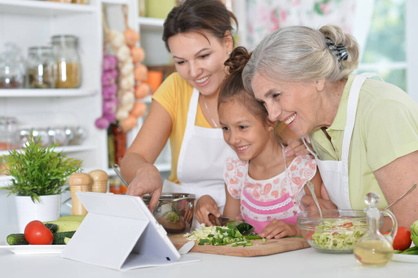 Portrait of happy family coocking salad at kitchen - Zdjęcie, obraz