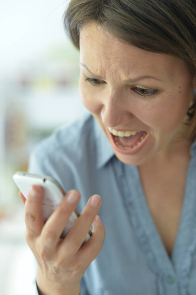 Close-up of a woman screaming at mobile phone - Fotografie, Obrázek