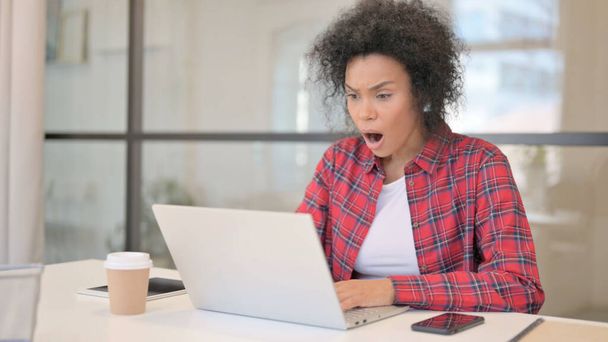 Afrikaanse vrouw reageert op verlies tijdens het gebruik van laptop - Foto, afbeelding