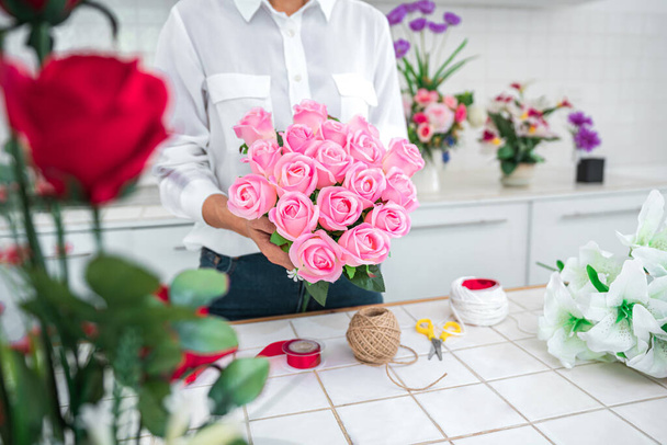 Organiser la décoration de fleurs artificielles à la maison, travail de fleuriste de jeune femme faisant l'organisation de fleurs artificielles bricolage, artisanat et concept fait main. - Photo, image