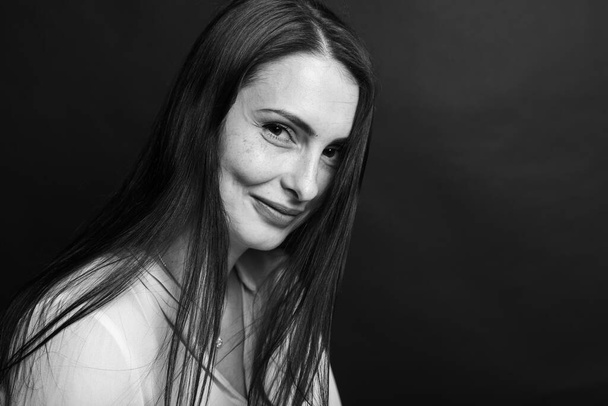Portrait noir et blanc, prise de vue en studio, d'une jolie jeune fille d'âge moyen, jolie et émotionnelle, sur fond sombre - Photo, image