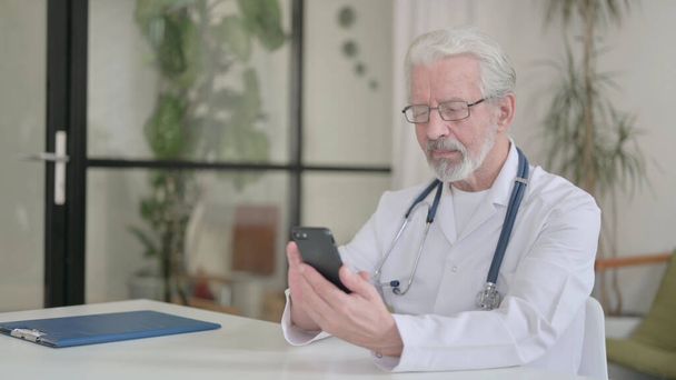 Senior Old Doctor using Smartphone in Clinic - Foto, afbeelding