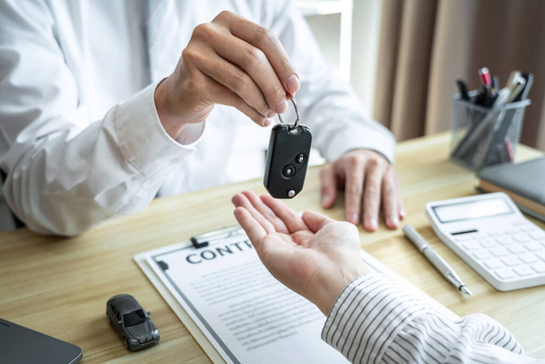 Salesman agent sending a key to customer after the good deal agreement, successful car loan insurance contract buying or selling new vehicle. - Fotoğraf, Görsel