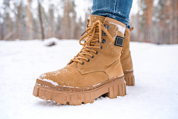 Women's feet in yellow boots in the snow in a snowy forest - Foto, Imagem