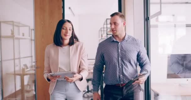 4k video footage of two young business colleagues chatting as they walk though the office - Video, Çekim