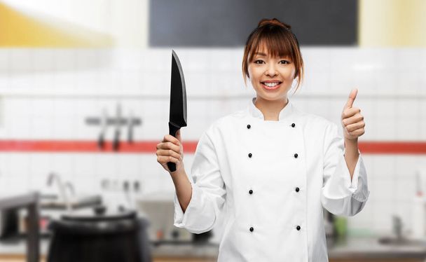 smiling female chef with knife showing thumbs up - Zdjęcie, obraz
