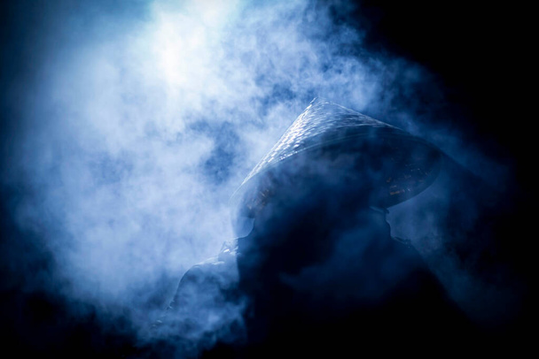 Egy vietnámi kalapos férfi a fagy közepén éjszaka a füst körül. - Fotó, kép