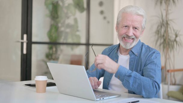 Senior Old Man Smiling at Camera while using Laptop - Photo, image