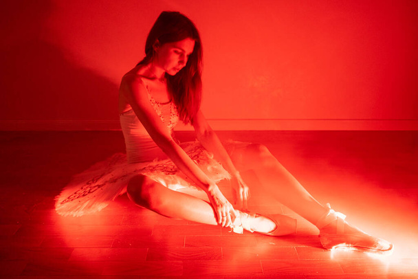 Ballerine avec de longues jambes posant en lumière rouge - Photo, image