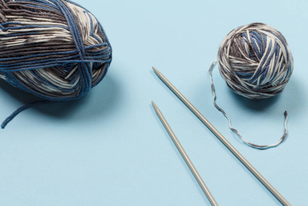 青い背景に糸玉と金属編み針を編む。編み物の概念。トップ表示. - 写真・画像