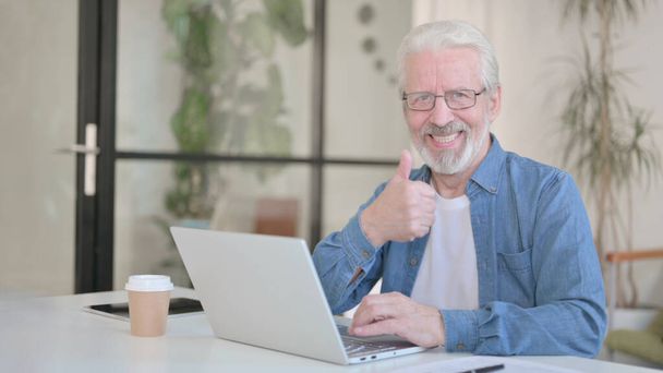 Senior Old Man showing Thumbs Up while using Laptop in Office - Foto, Imagen