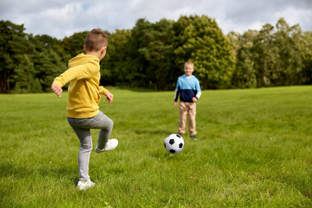 happy little boys with ball playing soccer at park - Foto, imagen