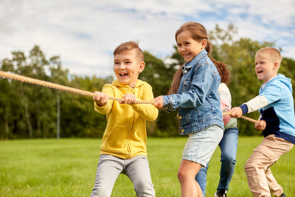 happy children playing tug-of-war game at park - Fotografie, Obrázek