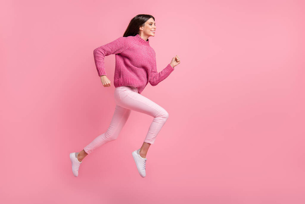 Full size profile photo of brunette nice girl jump run wear pink sweater pants sneakers isolated on crimson background. - 写真・画像