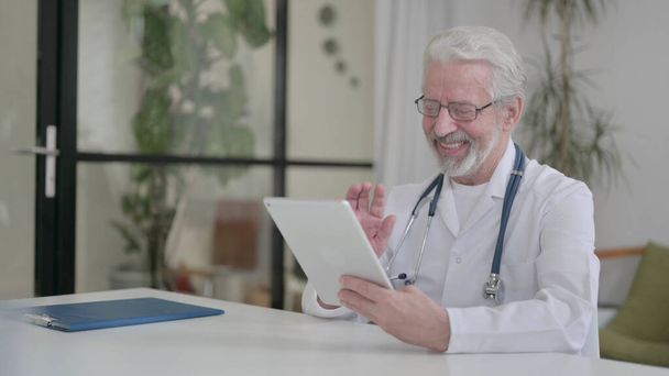 Senior Old Doctor making Video Call on Tablet in Clinic - Photo, image