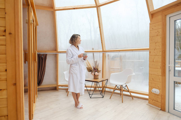 A young woman in a white bathrobe enjoys spa treatments in the sauna. Spa complex. - Photo, image