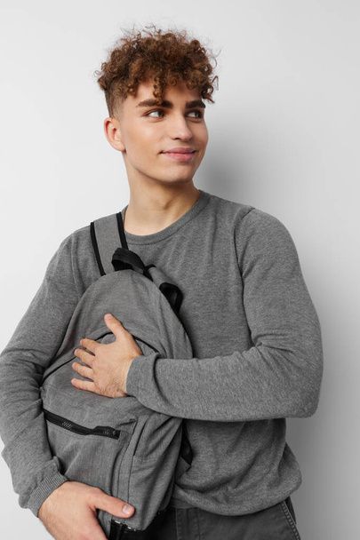 handsome young man in a gray sweater backpack fashion isolated background - Foto, Bild