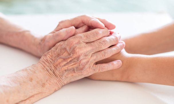 Руки дитини в руках бабусі, стара коричнева шкіра в літній жінці, материнська любов і догляд
. - Фото, зображення