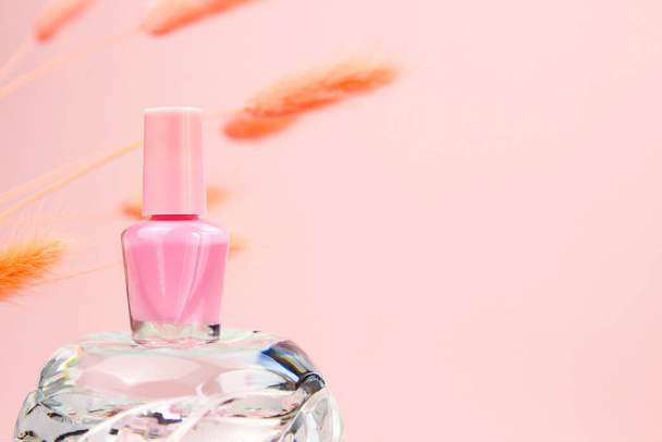 Nail polish small glass bottle on glass or crystal podium and peach lagurus herbs on pink background. Unbranded mockup with copy space. Professional manicure concept. - Foto, Imagem