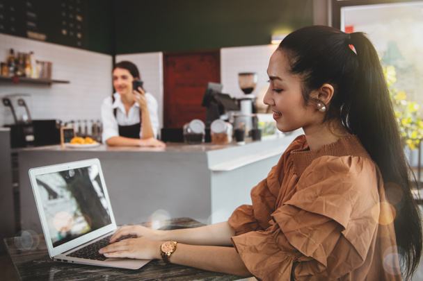 Бизнес-леди является клиенткой интернет-сервиса wi-fi. Сидеть за письменным столом с ноутбуком в кофейне - отличный сервис, за прилавком - женщины-бариста. - Фото, изображение