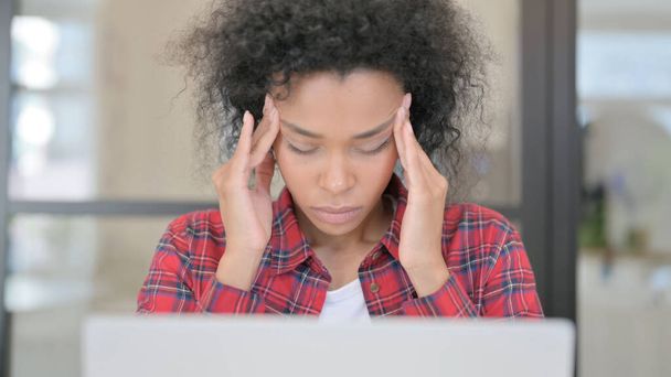 close-up van Afrikaanse vrouw met hoofdpijn tijdens het gebruik van laptop - Foto, afbeelding